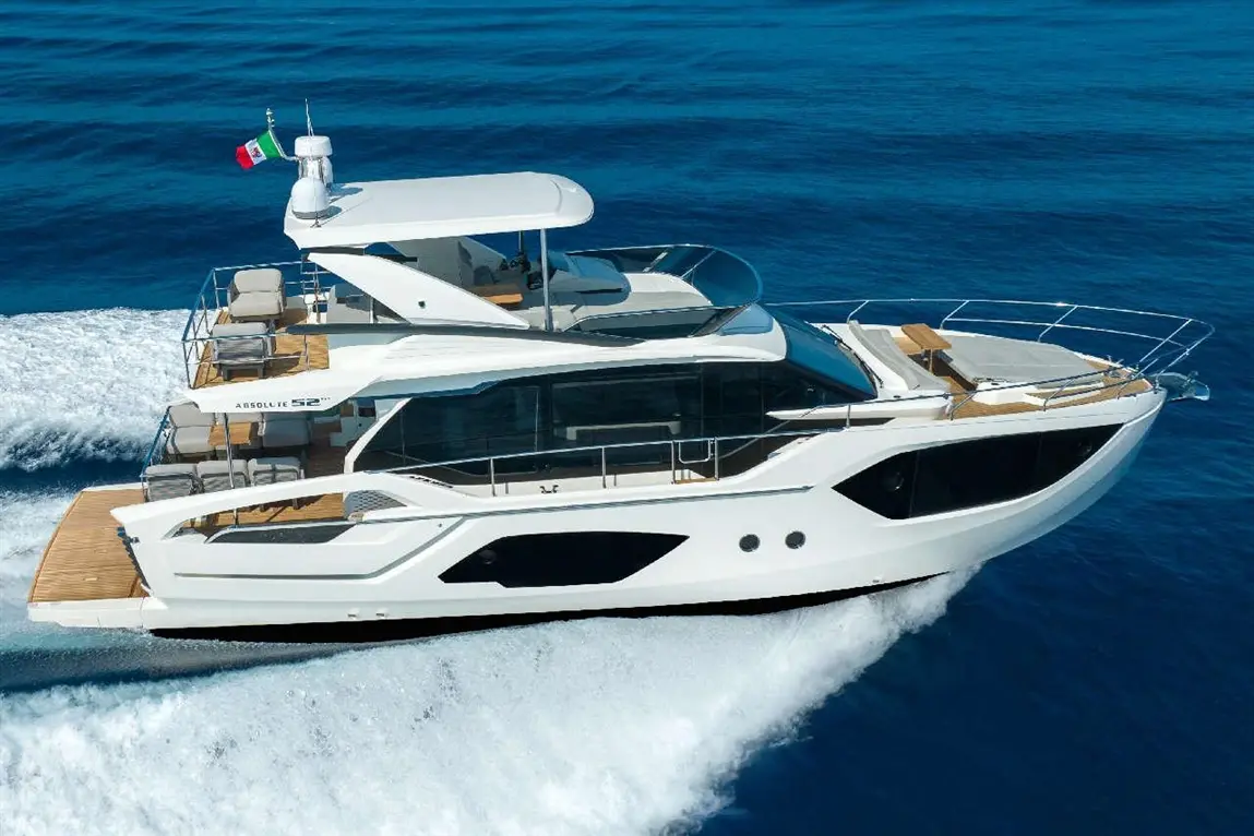A sleek white motor yacht, Absolute 52, cruises through azure waters, featuring stylish seating and the Italian flag.